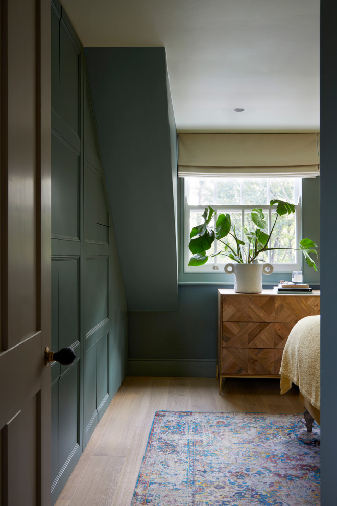 Design ideas for a medium sized classic master bedroom in London with green walls, medium hardwood flooring, beige floors and panelled walls.