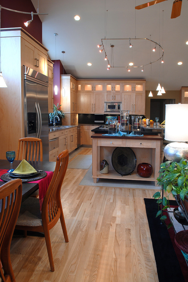 Inspiration för mellanstora moderna flerfärgat kök, med en undermonterad diskho, skåp i shakerstil, skåp i ljust trä, granitbänkskiva, svart stänkskydd, rostfria vitvaror, ljust trägolv, en köksö och brunt golv