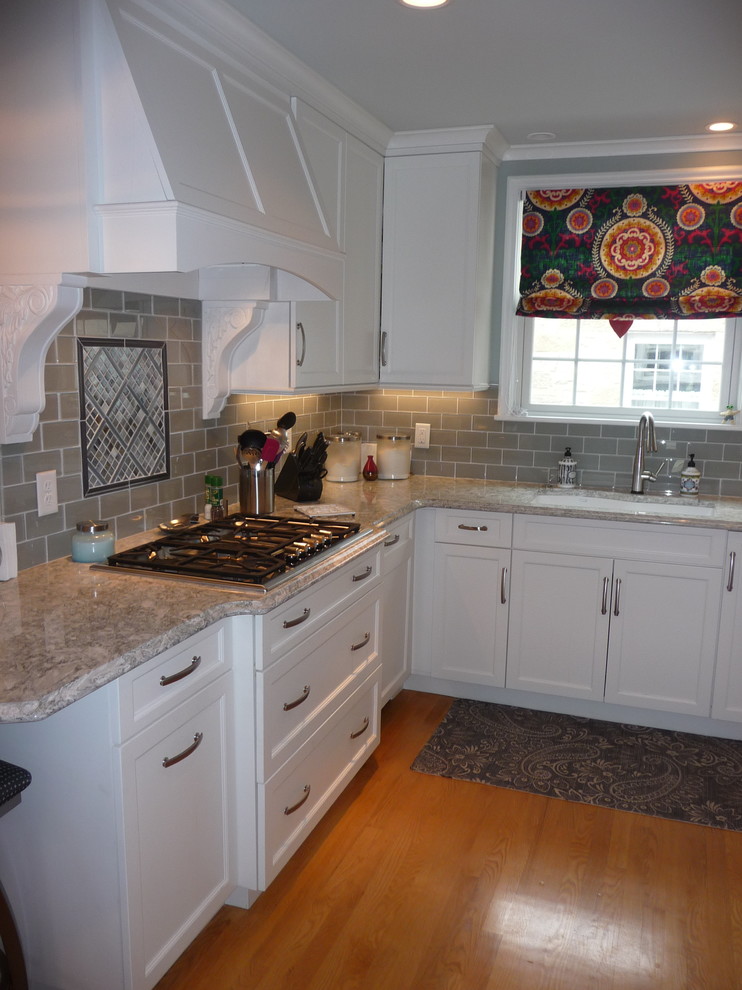 Inspiration for an u-shaped light wood floor enclosed kitchen remodel in Milwaukee with an undermount sink, glass tile backsplash and stainless steel appliances
