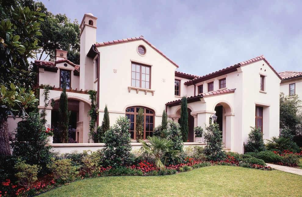 This is an example of a large mediterranean two-storey stucco beige house exterior in Dallas with a gable roof and a tile roof.