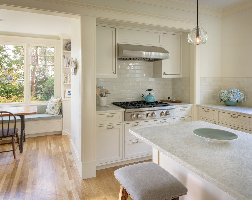 Inspiration for a mid-sized transitional light wood floor kitchen remodel in Seattle with shaker cabinets, white cabinets, quartzite countertops, blue backsplash, ceramic backsplash, stainless steel appliances and an island