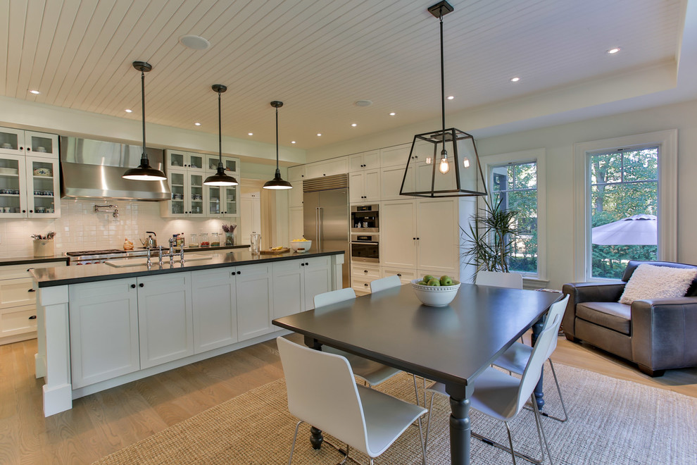 Inspiration for a large transitional galley light wood floor eat-in kitchen remodel in Toronto with shaker cabinets, white cabinets, quartz countertops, stainless steel appliances, an undermount sink, white backsplash, subway tile backsplash and an island