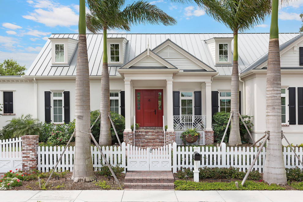 Photo of a mid-sized traditional one-storey beige house exterior in Tampa with a metal roof.