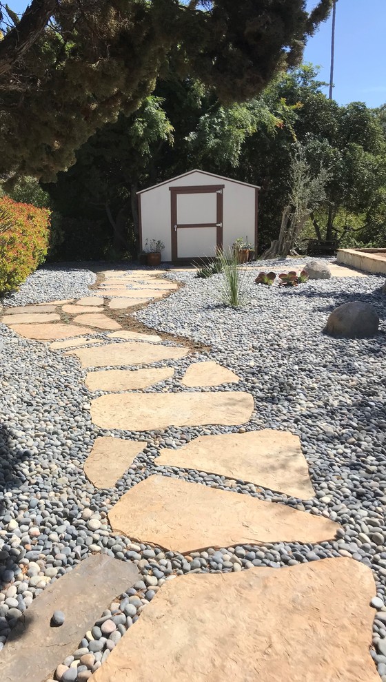 Small mediterranean side yard full sun xeriscape in San Diego with a garden path and natural stone pavers.