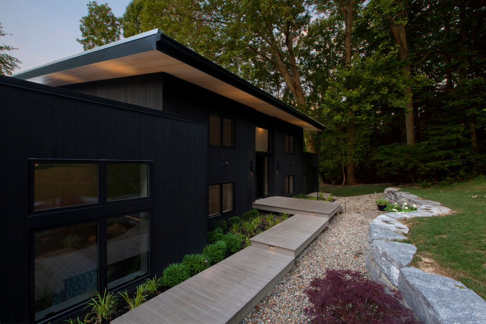 This is an example of a mid-sized modern two-storey black house exterior in Indianapolis with wood siding, a shed roof and a metal roof.