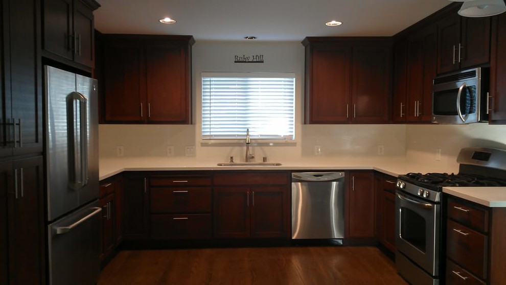 Mid-sized transitional u-shaped medium tone wood floor and brown floor kitchen photo in San Francisco with an undermount sink, shaker cabinets, dark wood cabinets, granite countertops, stone slab backsplash, stainless steel appliances and white backsplash