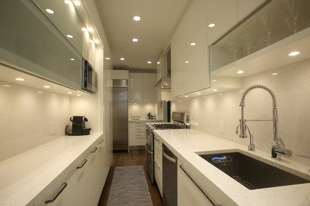 Design ideas for a mid-sized modern galley separate kitchen in New York with an undermount sink, flat-panel cabinets, white cabinets, stainless steel appliances, medium hardwood floors, no island, terrazzo benchtops, white splashback and stone tile splashback.