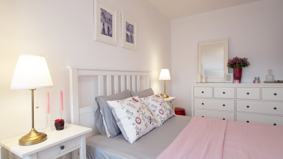 Modelo de dormitorio principal romántico grande con paredes blancas, suelo de madera clara y suelo marrón