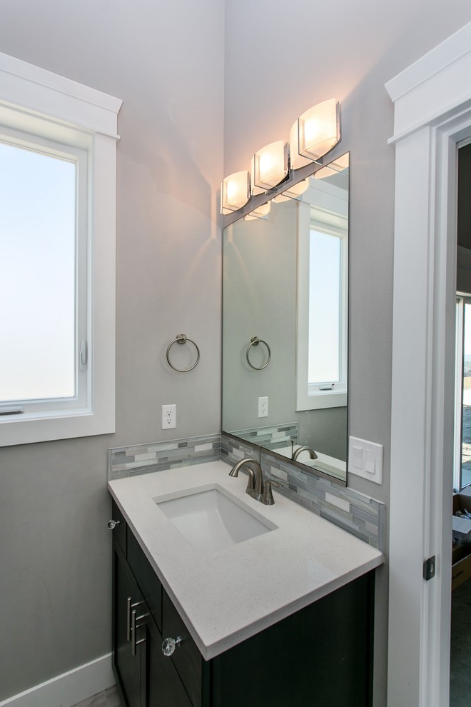 Small transitional 3/4 gray tile and mosaic tile porcelain tile and gray floor alcove shower photo in Seattle with shaker cabinets, dark wood cabinets, a two-piece toilet, gray walls, an undermount sink, quartz countertops, a hinged shower door and white countertops