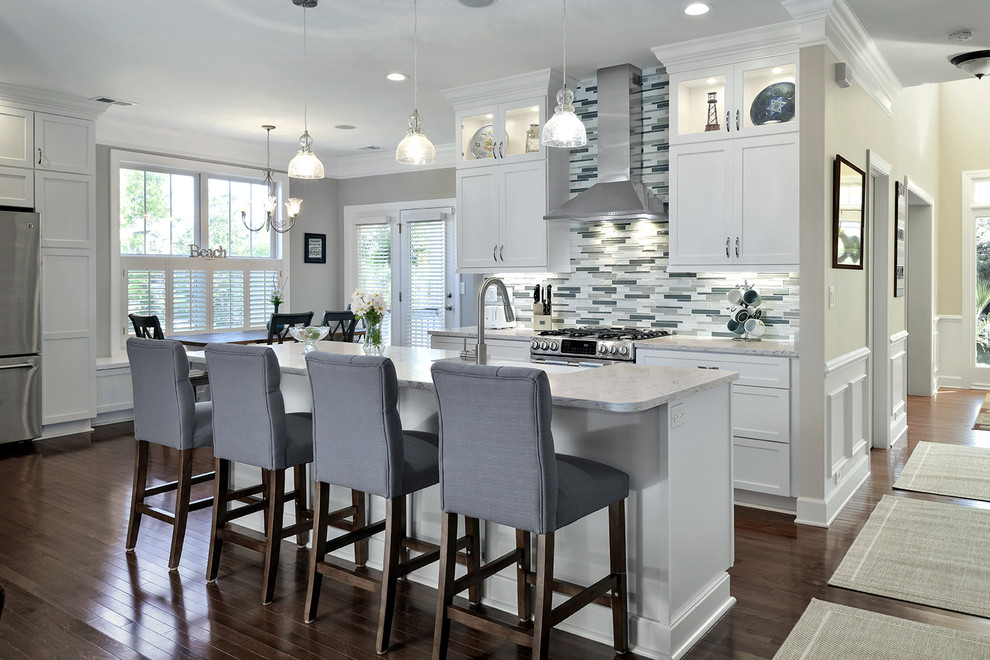 This is an example of a mid-sized contemporary single-wall eat-in kitchen in Charleston with a farmhouse sink, shaker cabinets, white cabinets, quartz benchtops, grey splashback, glass tile splashback, stainless steel appliances, dark hardwood floors and with island.