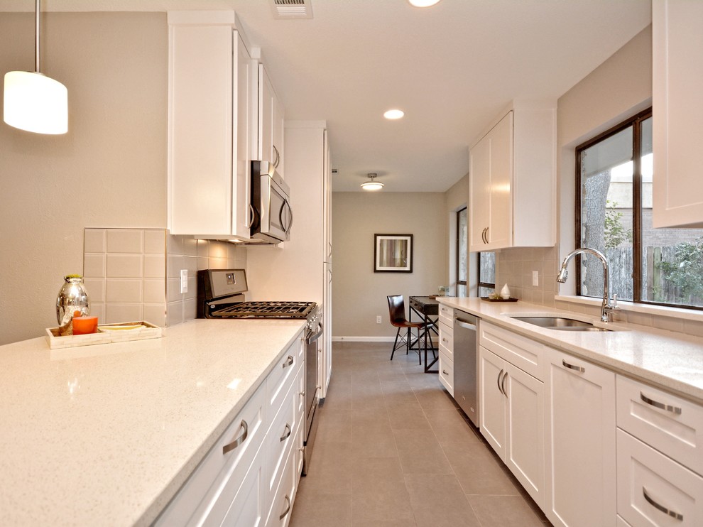 Open concept kitchen - mid-sized transitional galley porcelain tile open concept kitchen idea in Austin with an undermount sink, shaker cabinets, white cabinets, quartzite countertops, gray backsplash, glass tile backsplash and stainless steel appliances