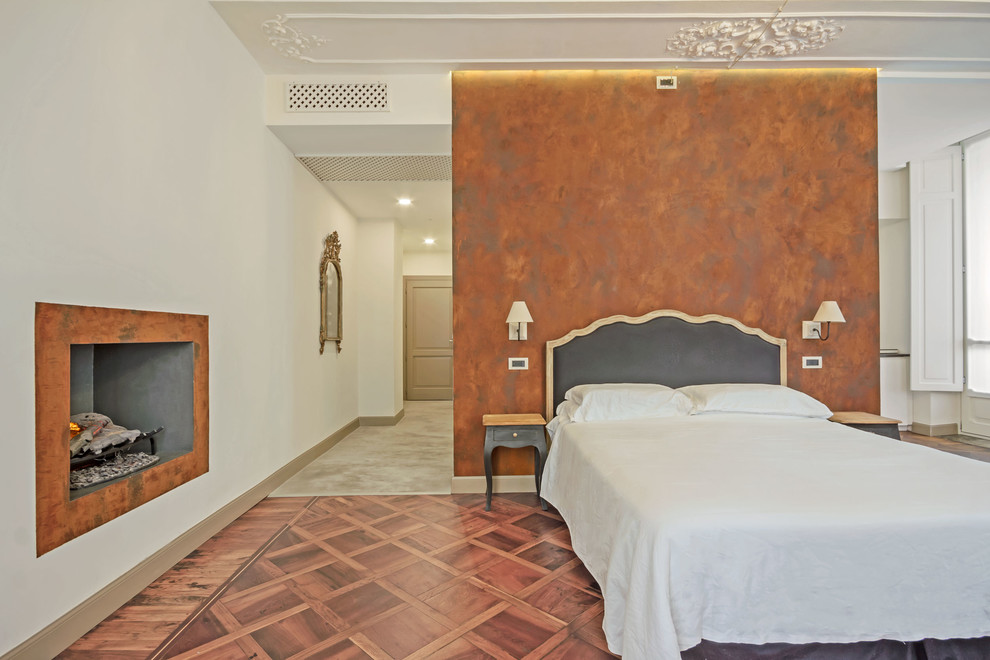 Traditional master bedroom in Turin with white walls, a standard fireplace and brown floor.