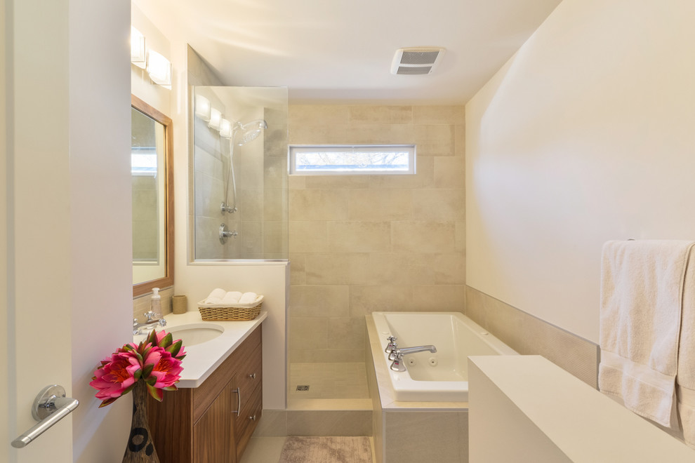 This is an example of a small contemporary 3/4 bathroom in Orange County with flat-panel cabinets, medium wood cabinets, a drop-in tub, an alcove shower, beige tile, porcelain tile, white walls, porcelain floors, an undermount sink, solid surface benchtops, beige floor and an open shower.