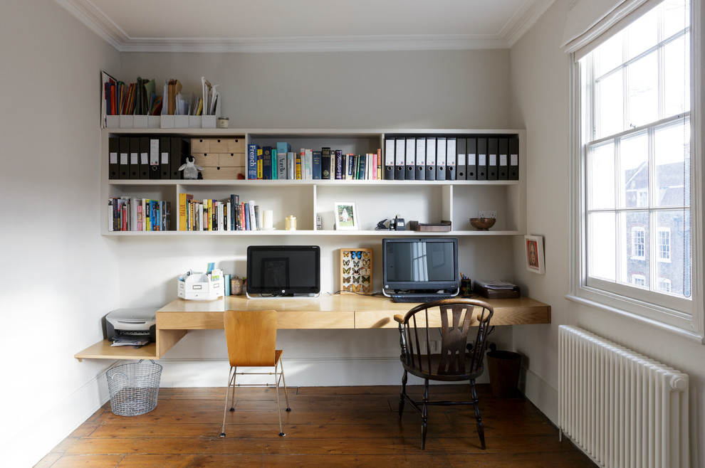 Design ideas for a medium sized contemporary study in London with white walls, medium hardwood flooring, a built-in desk and brown floors.