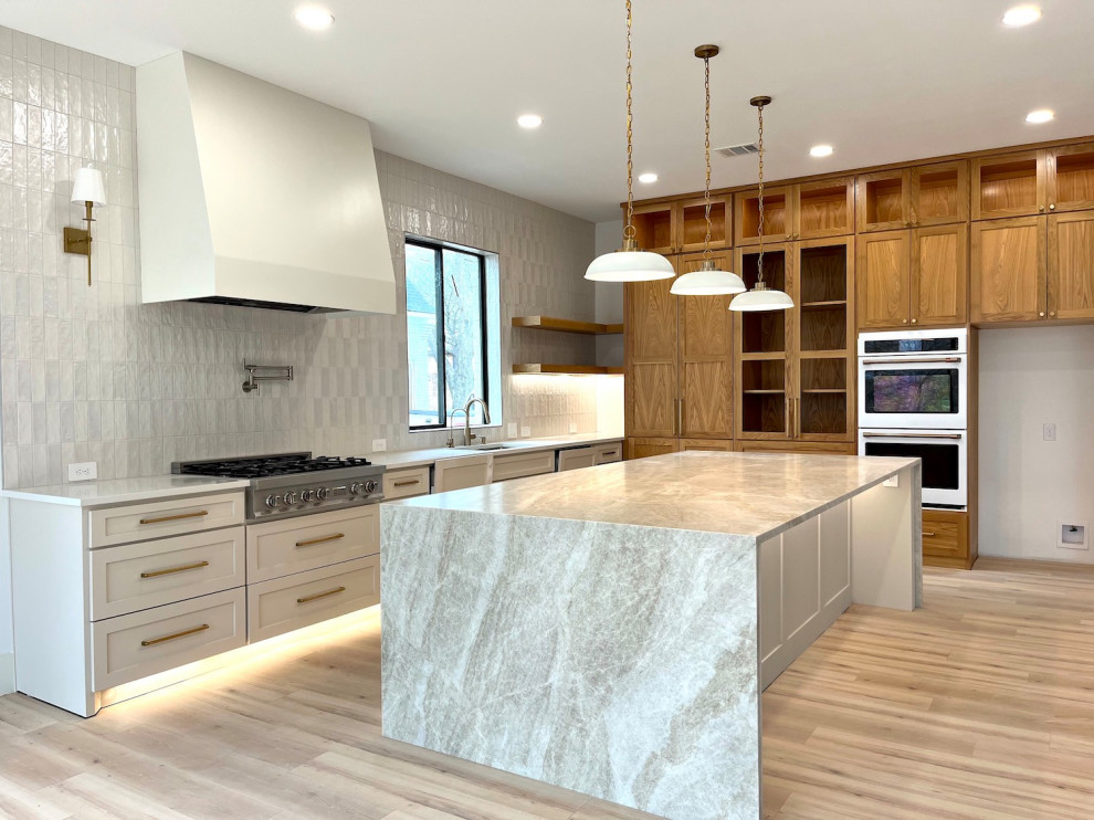 This is an example of an expansive contemporary kitchen/diner in Dallas with a single-bowl sink, shaker cabinets, beige cabinets, quartz worktops, beige splashback, ceramic splashback, stainless steel appliances, laminate floors, an island, beige floors and beige worktops.