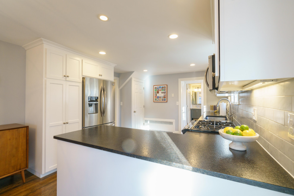 Small transitional u-shaped medium tone wood floor and brown floor eat-in kitchen photo in Other with an undermount sink, shaker cabinets, white cabinets, granite countertops, white backsplash, marble backsplash, stainless steel appliances, a peninsula and black countertops