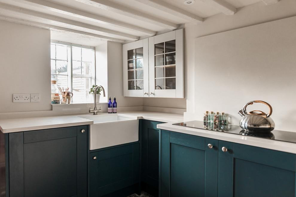 Photo of a small scandinavian u-shaped separate kitchen in Other with a farmhouse sink, shaker cabinets, blue cabinets, quartzite benchtops, white splashback, engineered quartz splashback, black appliances, slate floors, no island, black floor and yellow benchtop.