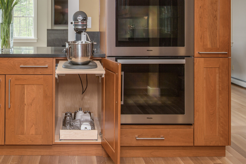 Transitional u-shaped medium tone wood floor kitchen photo in Boston with an undermount sink, shaker cabinets, medium tone wood cabinets, quartz countertops, gray backsplash, stone slab backsplash, stainless steel appliances and an island