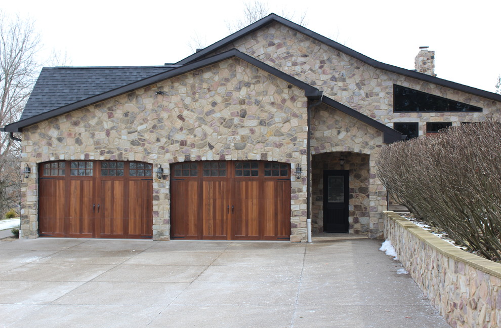 Large country two-storey beige house exterior in Other with stone veneer, a gable roof and a shingle roof.