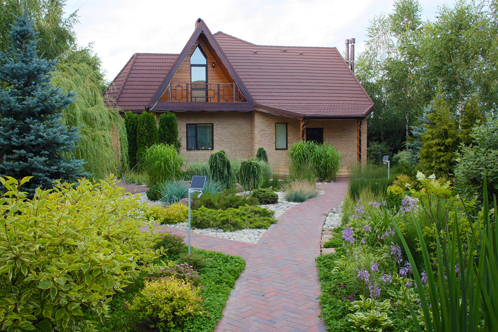This is an example of a mid-sized traditional partial sun formal garden for summer in Moscow with brick pavers and a garden path.