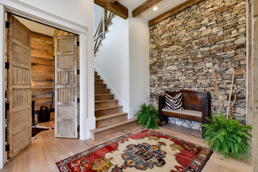 Photo of a country foyer in Austin with light hardwood floors and exposed beam.