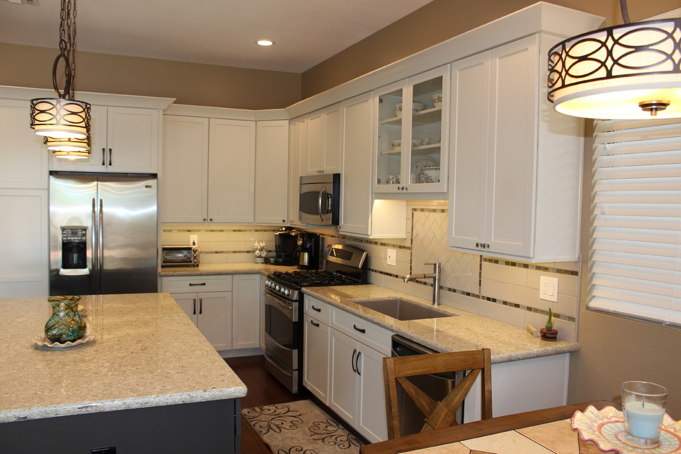 Open concept kitchen - mid-sized transitional l-shaped dark wood floor and brown floor open concept kitchen idea in Phoenix with an undermount sink, shaker cabinets, white cabinets, granite countertops, white backsplash, subway tile backsplash, stainless steel appliances and an island