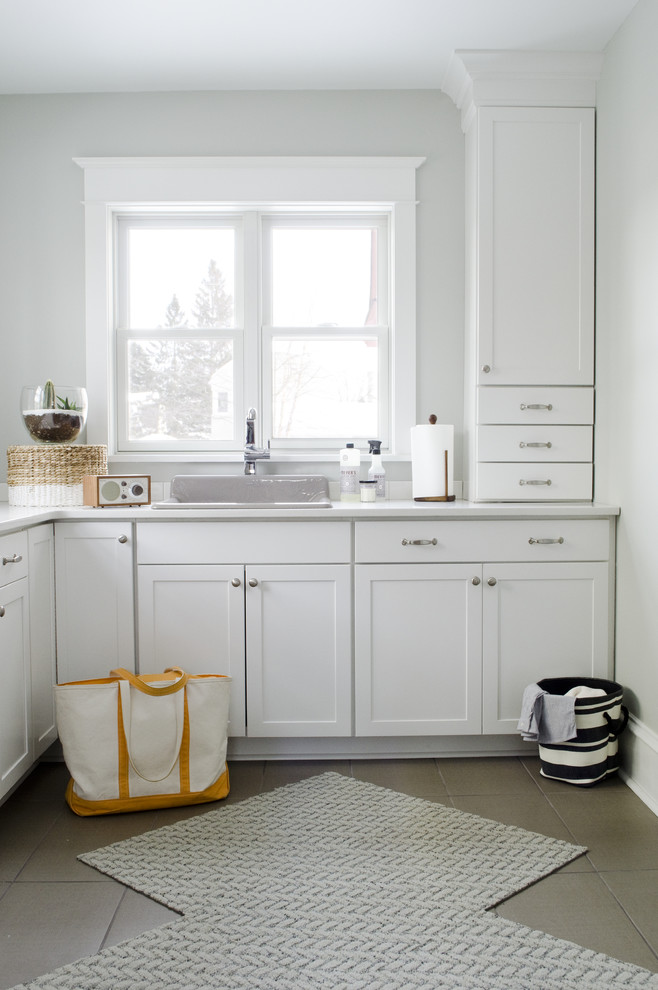 Photo of a large transitional l-shaped utility room in Other with shaker cabinets, white cabinets, white walls and ceramic floors.