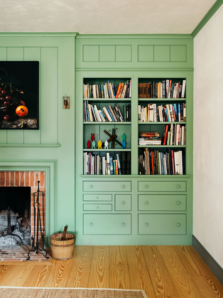 Photo of a country family room in New York with green walls, light hardwood floors and a brick fireplace surround.