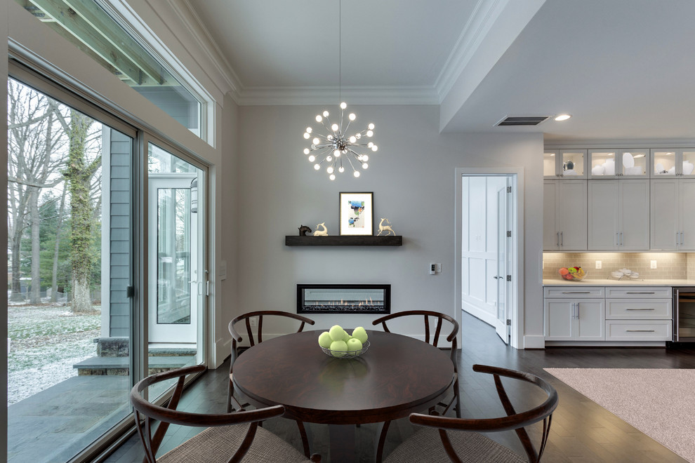 Example of a mid-sized transitional dark wood floor dining room design in DC Metro with beige walls and a two-sided fireplace