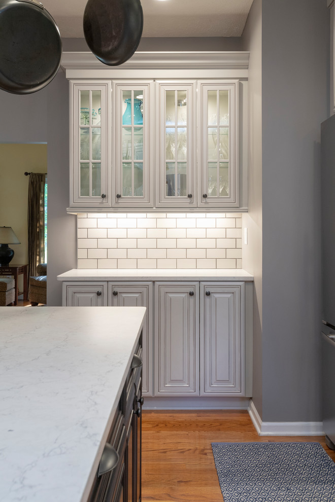 Inspiration for a mid-sized transitional l-shaped medium tone wood floor and red floor eat-in kitchen remodel with an undermount sink, raised-panel cabinets, gray cabinets, quartz countertops, gray backsplash, subway tile backsplash, stainless steel appliances, an island and white countertops