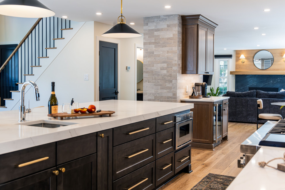 Inspiration for a mid-sized transitional medium tone wood floor kitchen remodel in DC Metro with a single-bowl sink, flat-panel cabinets, quartz countertops, white backsplash, quartz backsplash, stainless steel appliances, an island and white countertops