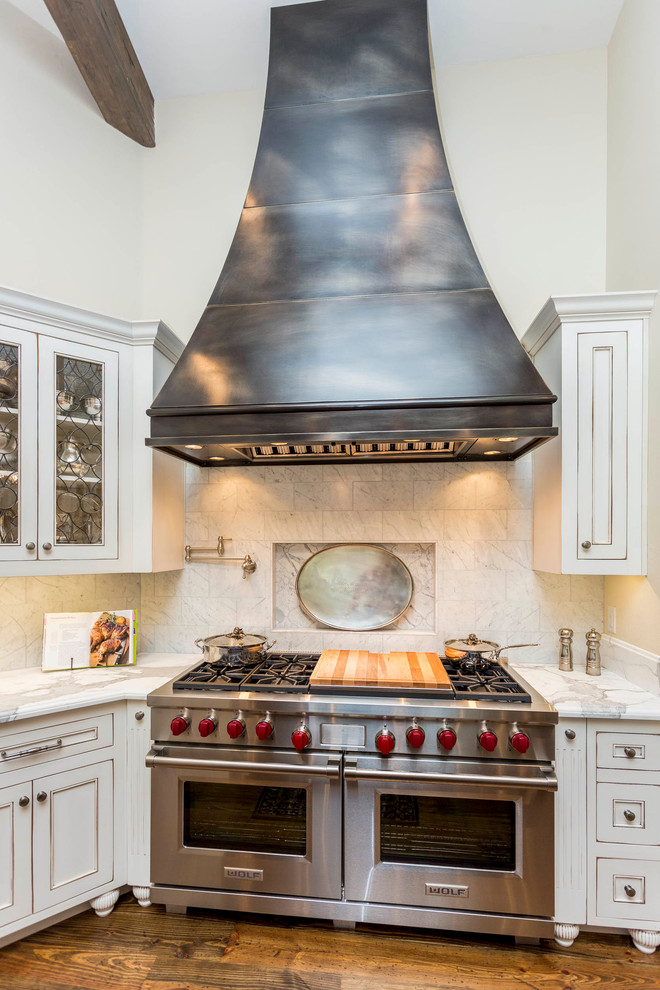 Inspiration for a large traditional l-shaped kitchen in Austin with beaded inset cabinets, white cabinets, marble benchtops, white splashback, stone tile splashback, stainless steel appliances and medium hardwood floors.
