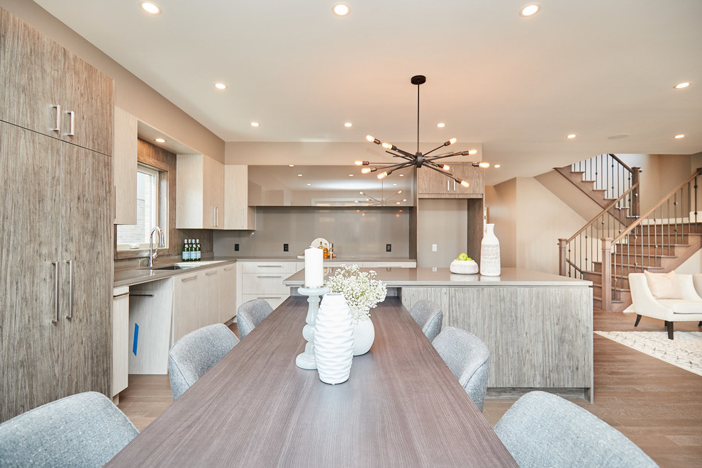 Example of a large transitional l-shaped medium tone wood floor and gray floor eat-in kitchen design with an undermount sink, flat-panel cabinets, gray cabinets, quartzite countertops, gray backsplash, stainless steel appliances, an island and gray countertops