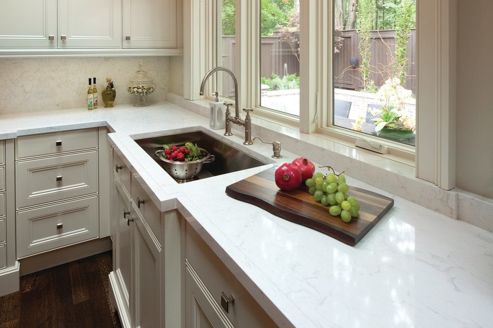 Inspiration for a mid-sized transitional l-shaped medium tone wood floor enclosed kitchen remodel in Milwaukee with recessed-panel cabinets, white cabinets, quartz countertops, white backsplash and stone slab backsplash