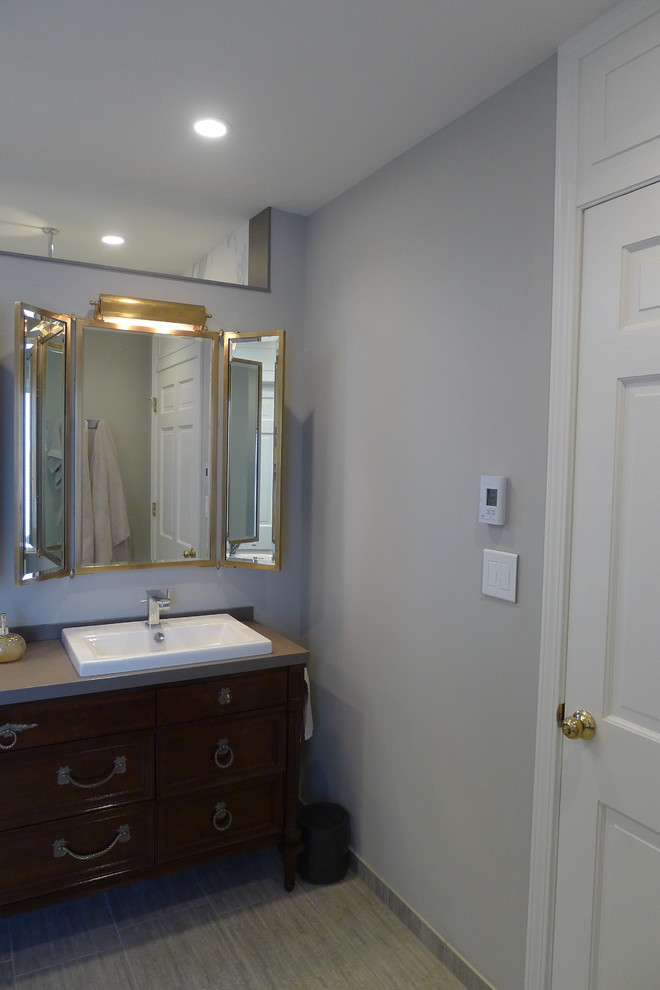 Example of a large transitional master gray tile and porcelain tile porcelain tile freestanding bathtub design in Indianapolis with a drop-in sink, furniture-like cabinets, dark wood cabinets, solid surface countertops, a one-piece toilet and gray walls