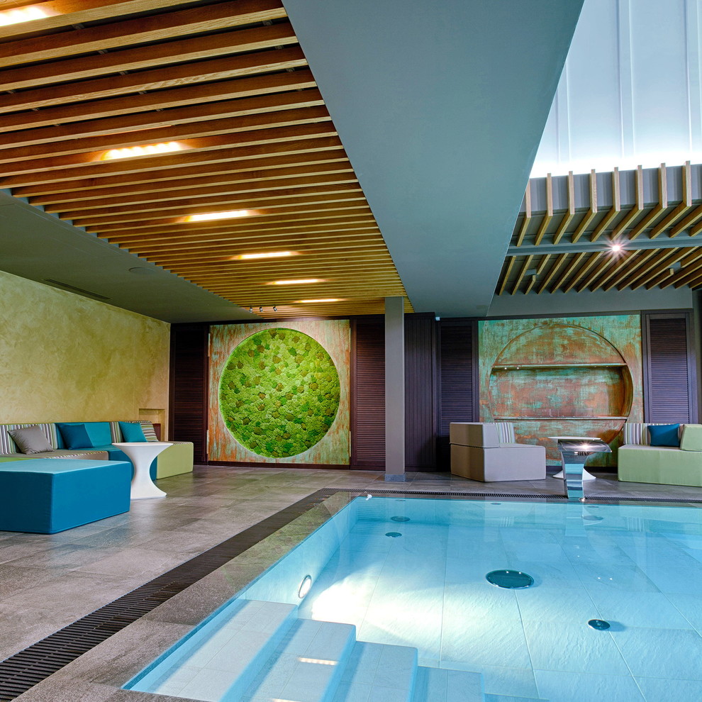 This is an example of a large industrial indoor rectangular infinity pool in Other with a water feature and tile.
