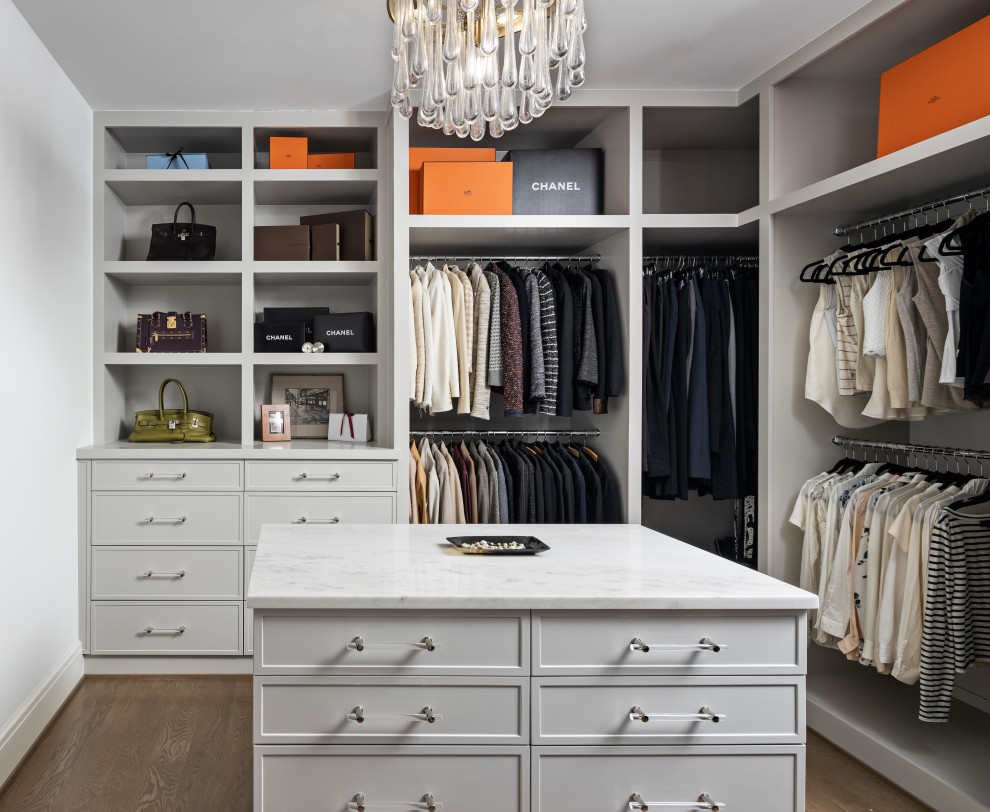 This is an example of a large transitional women's walk-in wardrobe in Detroit with shaker cabinets, grey cabinets, light hardwood floors and brown floor.