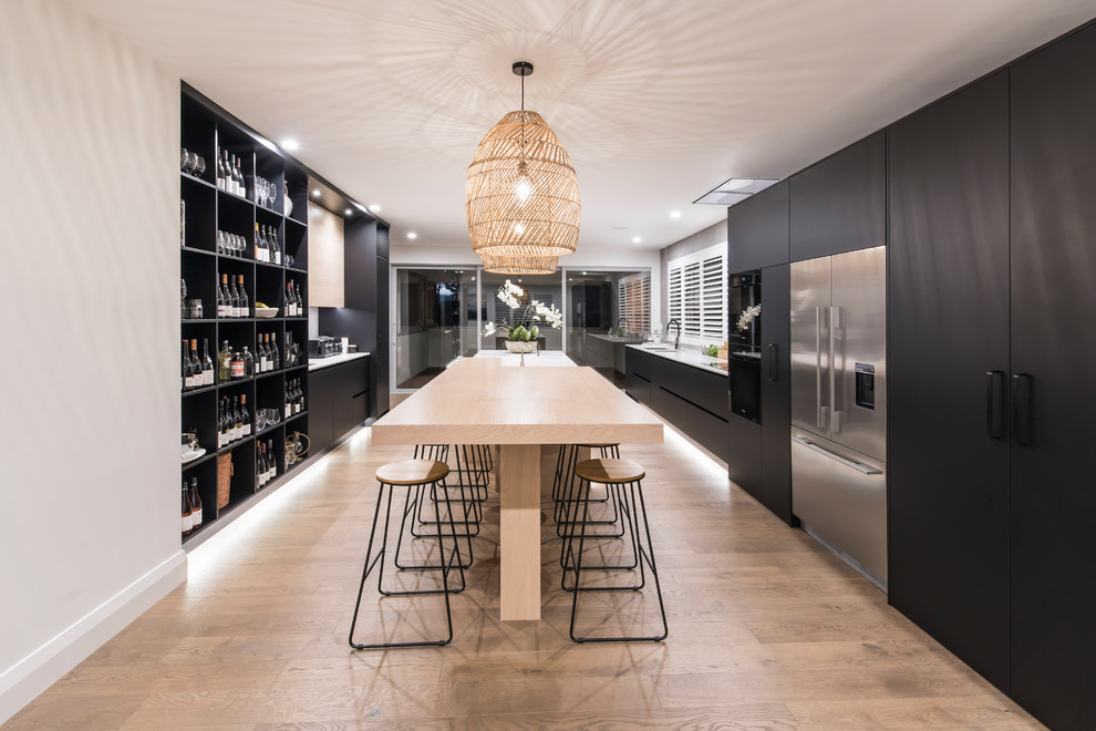 Design ideas for a large contemporary galley eat-in kitchen in Christchurch with an undermount sink, flat-panel cabinets, black cabinets, quartz benchtops, grey splashback, porcelain splashback, black appliances, light hardwood floors, with island and white benchtop.