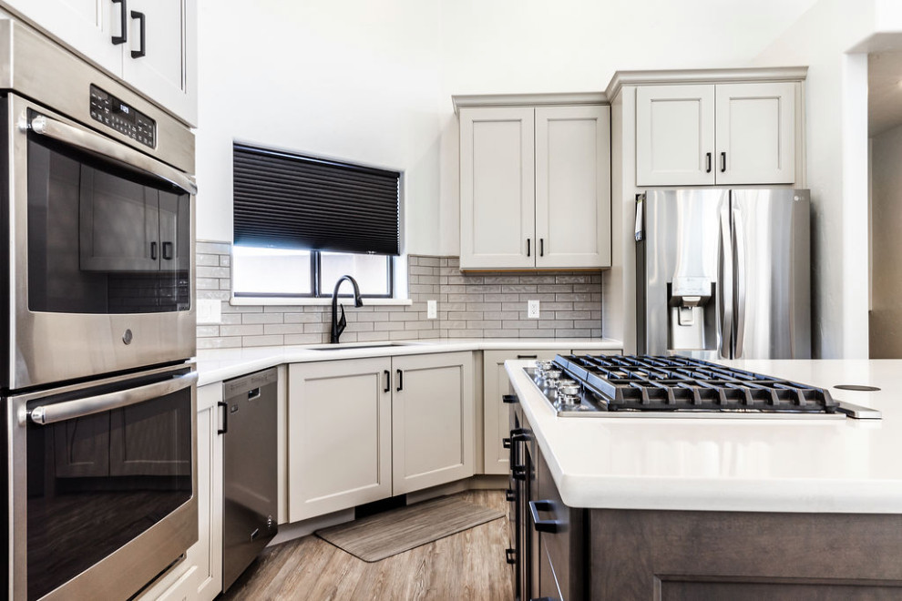 Large transitional u-shaped vinyl floor and gray floor eat-in kitchen photo with an undermount sink, shaker cabinets, gray cabinets, quartzite countertops, green backsplash, subway tile backsplash, stainless steel appliances, an island and white countertops