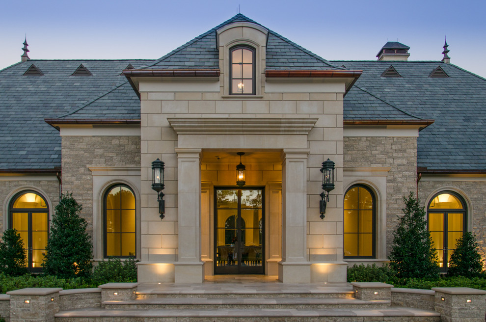 Photo of an expansive mediterranean beige exterior in Houston with stone veneer and a gable roof.