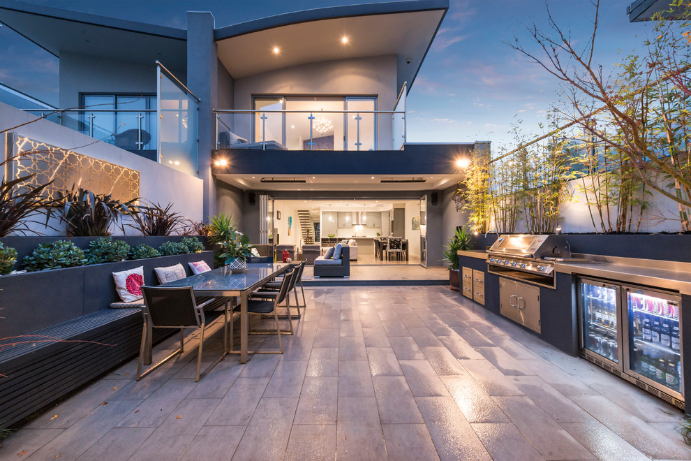 Expansive contemporary courtyard patio in Melbourne with an outdoor kitchen, tile and no cover.