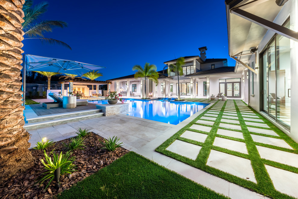 Ispirazione per un'ampia piscina a sfioro infinito mediterranea personalizzata dietro casa con paesaggistica bordo piscina e piastrelle