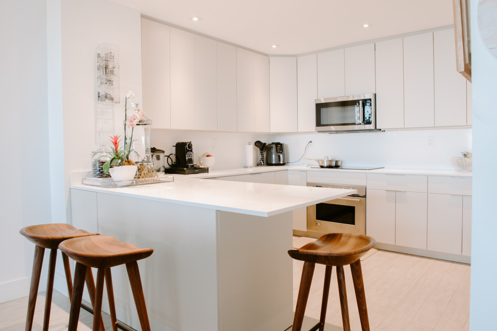 Mid-sized modern u-shaped eat-in kitchen in Miami with white cabinets, white splashback and white benchtop.