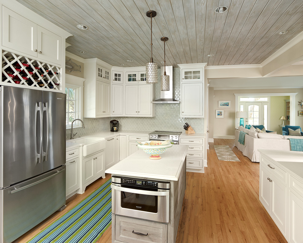 This is an example of a beach style kitchen in Charleston with a farmhouse sink, quartz benchtops, stainless steel appliances, light hardwood floors and with island.