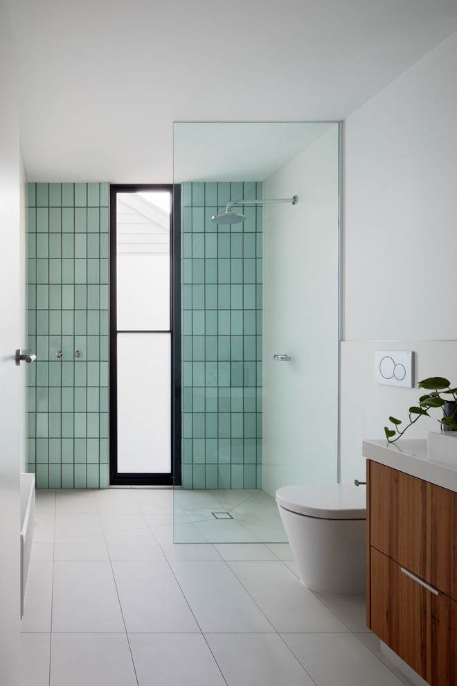 This is an example of a small contemporary 3/4 bathroom in Melbourne with flat-panel cabinets, medium wood cabinets, green tile, ceramic tile, white walls, ceramic floors, a drop-in sink, engineered quartz benchtops, beige floor, an open shower, white benchtops, a curbless shower and a one-piece toilet.