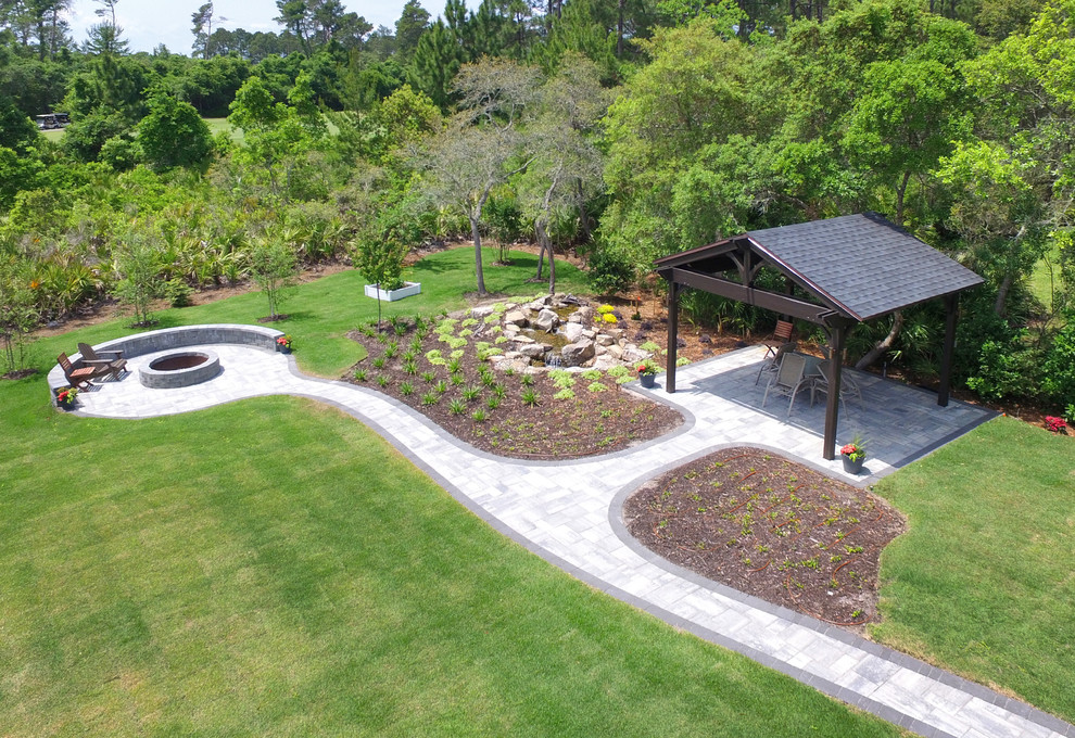 Expansive traditional backyard patio in Jacksonville with a water feature, stamped concrete and an awning.