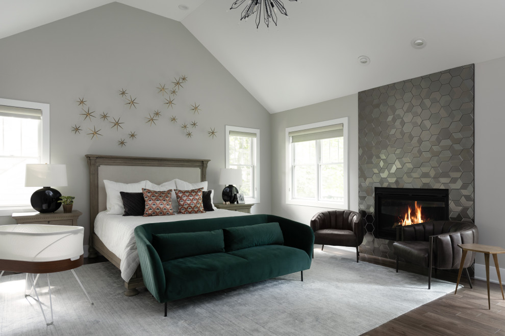 Design ideas for a transitional bedroom in Chicago with grey walls, dark hardwood floors, a standard fireplace, a tile fireplace surround, brown floor and vaulted.