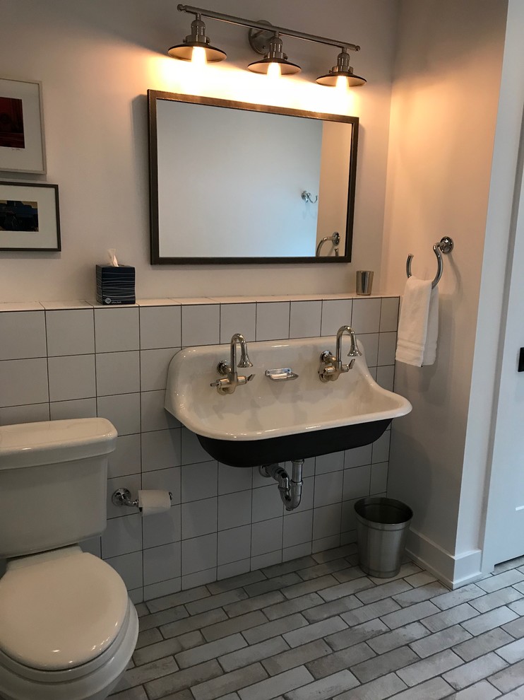 Inspiration for a mid-sized contemporary 3/4 bathroom in New York with an alcove shower, a two-piece toilet, white tile, ceramic tile, white walls, brick floors, a trough sink, solid surface benchtops, beige floor and a sliding shower screen.