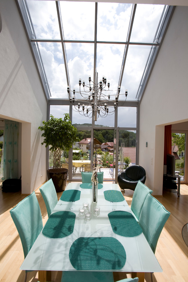 This is an example of a mid-sized contemporary open plan dining in Other with white walls and light hardwood floors.