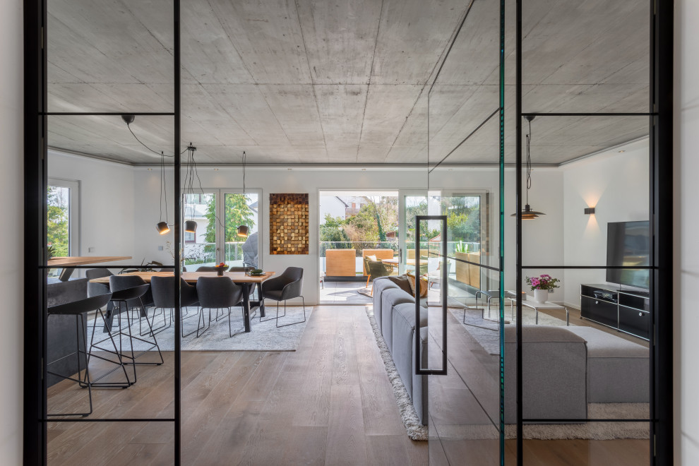 Offenes Modernes Wohnzimmer mit weißer Wandfarbe, braunem Holzboden und braunem Boden in Essen